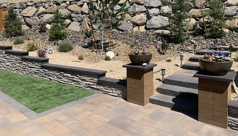 Professional landscaping with turf, retaining walls, concrete steps, and lighted pathways.